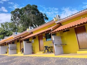 a row of yellow buildings with white doors at Chalésforquilha in Delfinópolis +17 photos