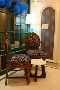 a room with two chairs and a table and a lamp at THE MASARA MANAR Hotel in Gwalior +8 photos
