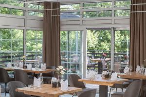 a restaurant with tables and chairs and windows at Fletcher Hotel-Restaurant Arnsberg-Sauerland in Arnsberg