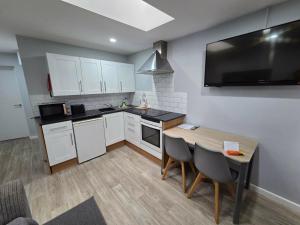 a kitchen with white cabinets and a table with chairs at 1B Smart Apartments in Newark-on-Trent +26 photos