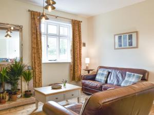 a living room with a leather couch and a table at Upper Broughton Farm Cottage in Snead