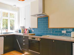 a kitchen with black cabinets and blue tiles at Upper Broughton Farm Cottage in Snead