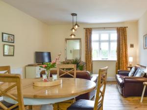 a living room with a dining room table and a couch at Upper Broughton Farm Cottage in Snead