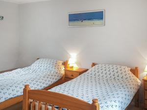 two beds in a bedroom with a picture of the ocean at Hen Ysgol in Llanfaethlu