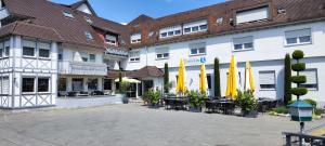a hotel with tables and yellow umbrellas in a courtyard at Hotel Hellers Twenty Four II -24h-Check-In- in Friedrichshafen