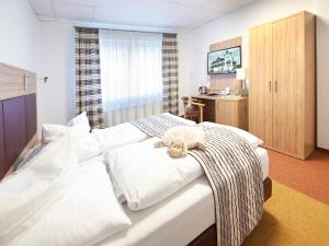 a bedroom with a bed with a teddy bear on it at Hotel Kronprinz in Bad Salzdetfurth
