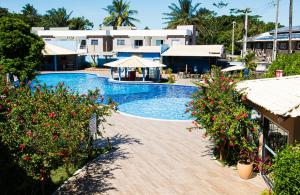 a swimming pool with flowers in front of a resort at Porto Mar Hotel in Porto Seguro
