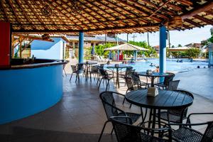 a restaurant with tables and chairs and a swimming pool at Porto Mar Hotel in Porto Seguro