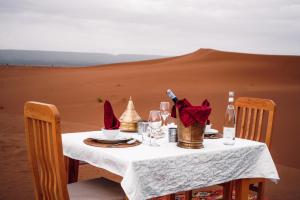 a table in the middle of a desert at Desert Luxury Camp Erg Chigaga in El Gouera