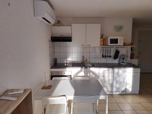 a kitchen with white cabinets and a table and chairs at Joli t2 valras plage in Valras-Plage