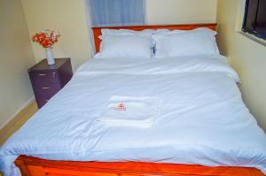 a bed with a white comforter with a red logo on it at FloJoy Haven in Machakos
