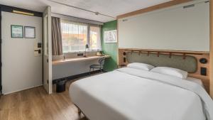a bedroom with a bed and a desk and a window at Campanile NATURE - Bordeaux Lac in Bordeaux +57 photos