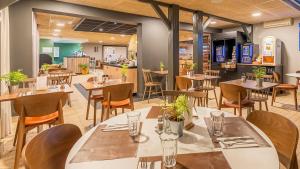 a restaurant with tables and chairs in a room at Campanile NATURE - Bordeaux Lac in Bordeaux