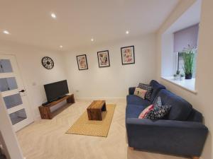 a living room with a blue couch and a tv at Ideal Lodgings in Radcliffe in Radcliffe