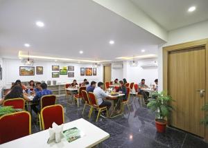 a group of people sitting at tables in a restaurant at Hotel Decent Suites - Delhi Airport in New Delhi
