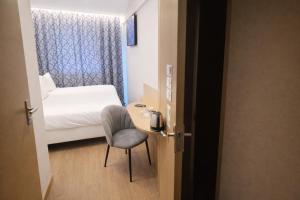 a room with a bed and a desk and a chair at Geographotel Paris-Roissy CDG Airport in Le Mesnil-Amelot +43 photos