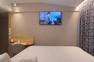 a hotel room with a bed and a tv on the wall at Geographotel Paris-Roissy CDG Airport in Le Mesnil-Amelot