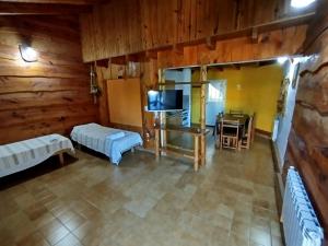 a room with two beds and a television and a table at Complejo El Alto in Tanti