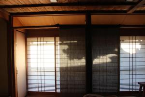 two windows in a room with the sun shining through at 檸檬草ー奄美の自然の香る宿ー in Amami