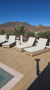a row of white lounge chairs on a deck at Casa Abuela Serapia in Tuineje