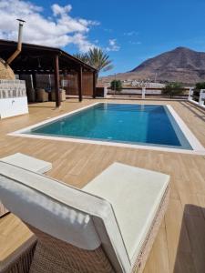 a swimming pool with a chair next to a house at Casa Abuela Serapia in Tuineje