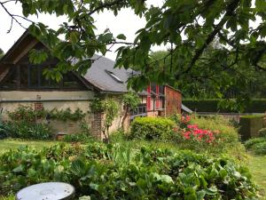 a garden in front of a house with flowers at La Forge de Paul et Virginie in Mainneville