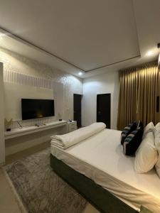 a large bedroom with a large bed and a flat screen tv at Nouveau Apartment in Abuja