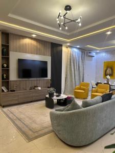 a living room with a couch and a tv at Nouveau Apartment in Abuja