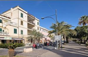 a street sign in front of a building with palm trees at Seafront, Large Studio on the Beach with AC and WiFi in Pietra Ligure