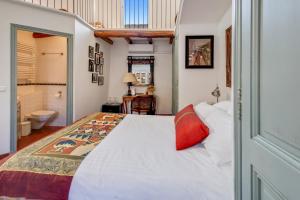a bedroom with a white bed and a bathroom at La Maison du Prince in Grimaud
