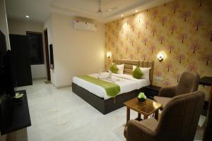 a hotel room with a bed and a woman sitting in a chair at The Leaf Farm in Ludhiana +8 photos