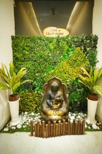a buddha statue in a garden with two plants at The Leaf Farm in Ludhiana