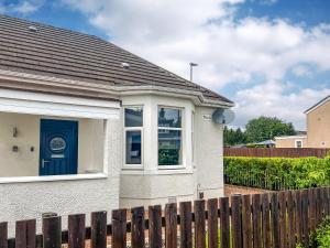 a white house with a blue door and a fence at Kirklea in Wishaw +7 photos