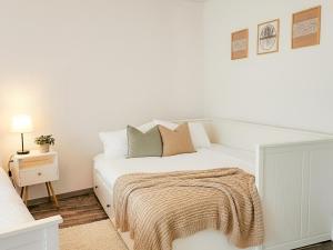a white bedroom with a bed and a night stand at Apartment Südwind - Beautiful premium apartment with 2 bedrooms near Rhine Falls & Zurich Airport in Klettgau in Klettgau