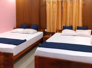 two beds in a room with blue and white sheets at Roy Guest House in Kānki