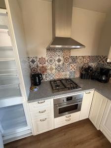 a kitchen with white cabinets and a stove top oven at Sint Anthonijshoek in Koudekerke