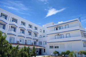 a white building with trees in front of it at Hotiday Castelsardo Spiaggia in Castelsardo
