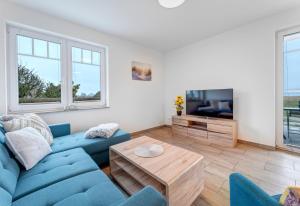 a living room with a blue couch and a tv at Haus Achterwasserblick 1 in Loddin