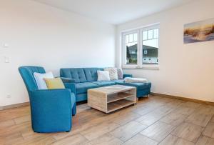 a living room with a blue couch and a table at Haus Achterwasserblick 1 in Loddin