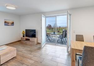 a living room with a television and a table and chairs at Haus Achterwasserblick 1 in Loddin