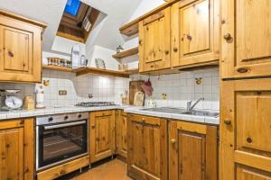 a kitchen with wooden cabinets and a sink at Hostdomus - Chalet Claviere in Claviere