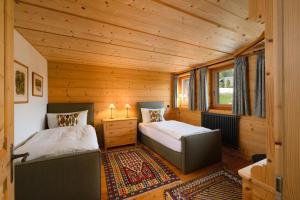 two beds in a small room with wooden walls at Chalet François in Champéry