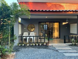 a house with two chairs on the front porch at Lanta Beautiful beach house 1 in Phra Ae beach