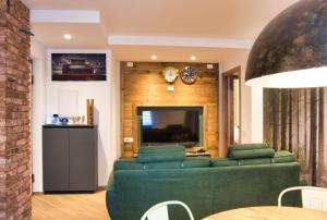 a living room with a green couch and a television at El Surcinel – Alpine Design Home in Ballabio