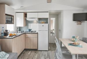 a kitchen with a white refrigerator and a table at Camping le Laha in Lesperon