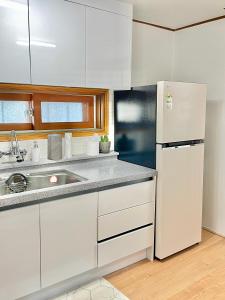 a kitchen with a white refrigerator and a sink at 강릉 44평 복층 독채 시아스테이 Gangneung Sia Stay in Gangneung