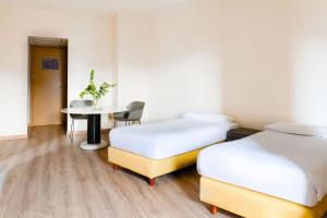 a hotel room with two beds and a table at B&B HOTEL Fabriano Janus in Fabriano
