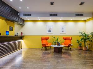 two orange chairs and a table in a lobby at B&B HOTEL Fabriano Janus in Fabriano