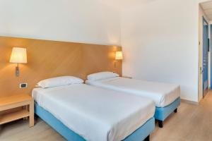 a hotel room with two beds and a table at B&B HOTEL Bergamo Executive in San Paolo D'Argon
