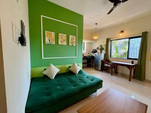a green couch in a living room with a table at The Habitat By Locomo in Mandrem